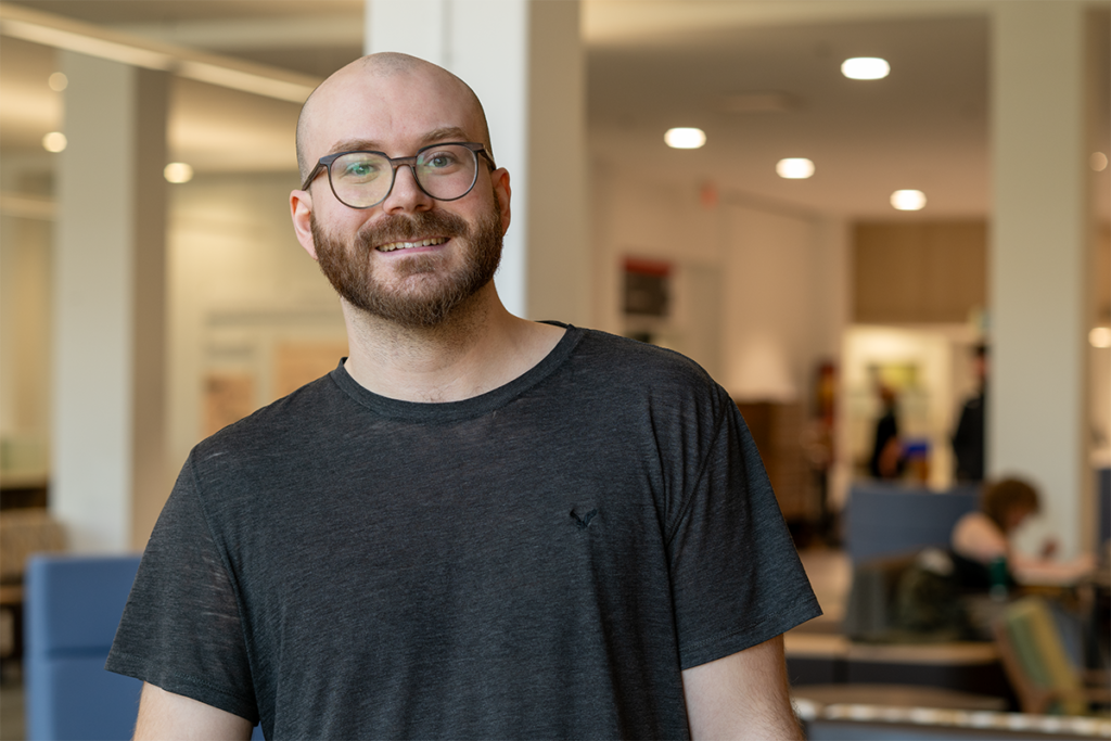 Joey Slinger standing in the MacOdrum Library at Carleton