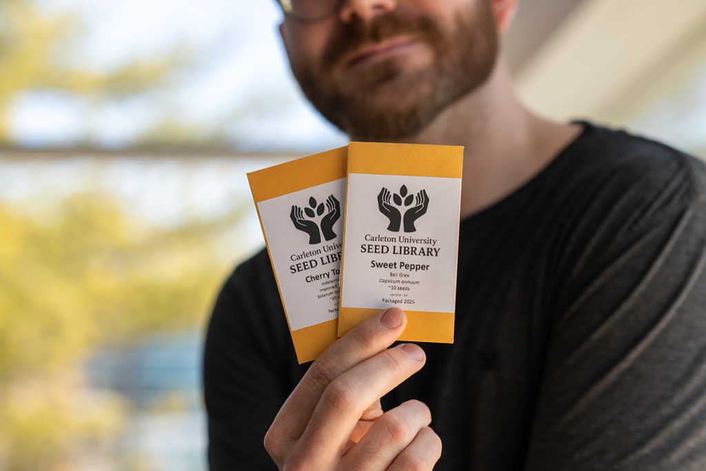 Joey Slinger holding up two packets of seeds.