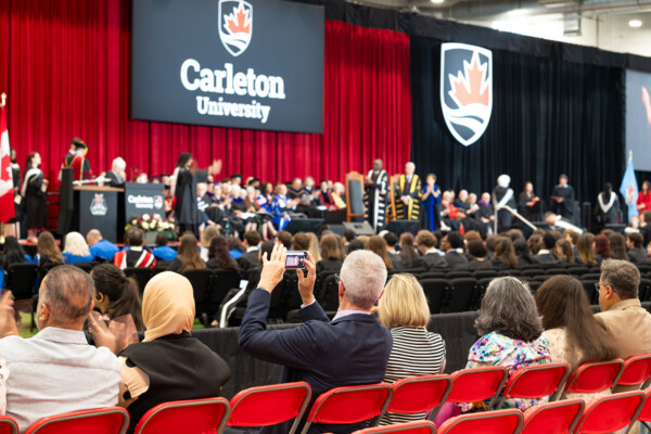 An audience watching and clapping as students cross the stage at convocation.