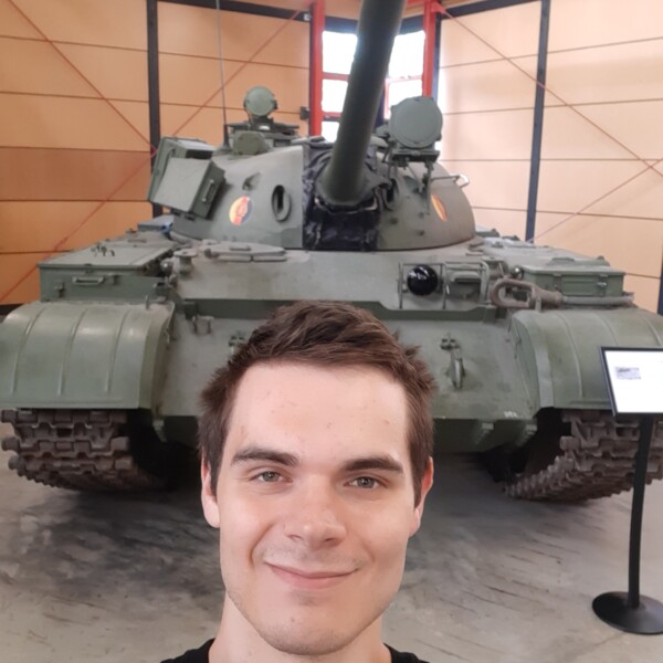 Student Ambassador with black t-shirt, standing in front of military tank in a museum