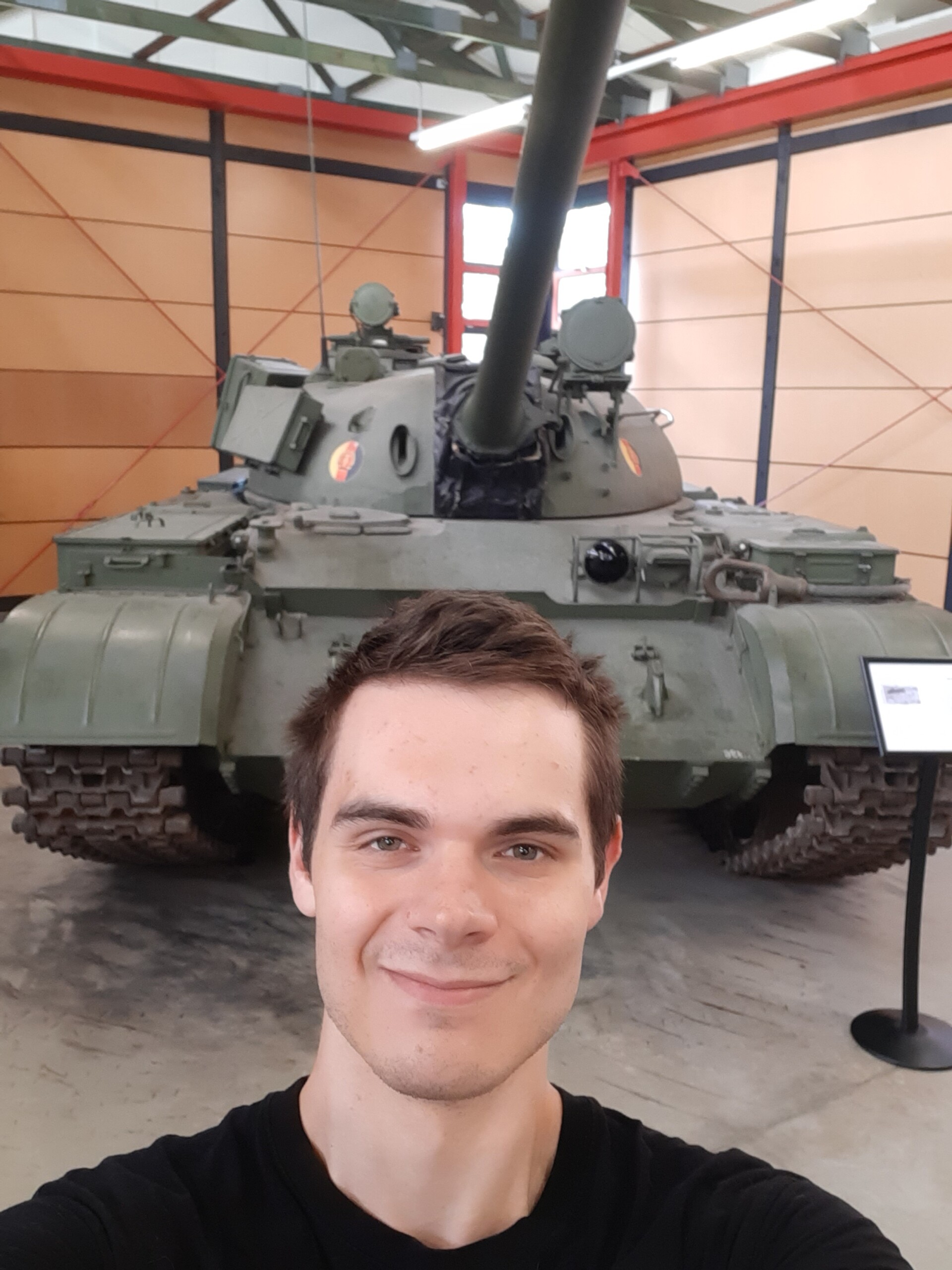 Student Ambassador with black t-shirt, standing in front of military tank in a museum