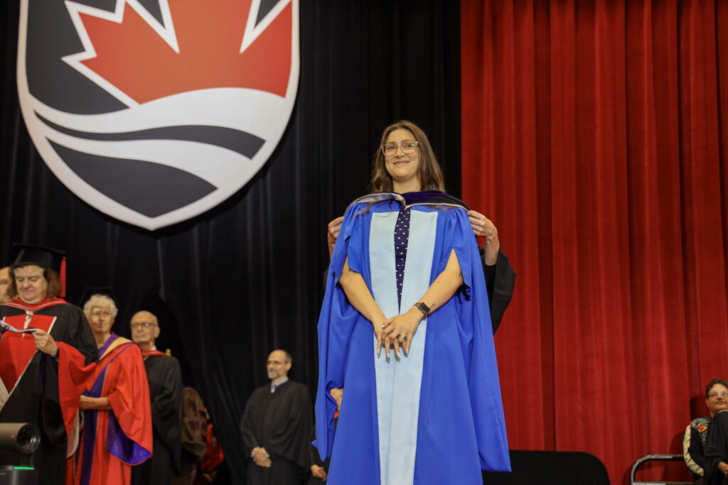 A doctoral student in blue robes on the stage at Convocation.