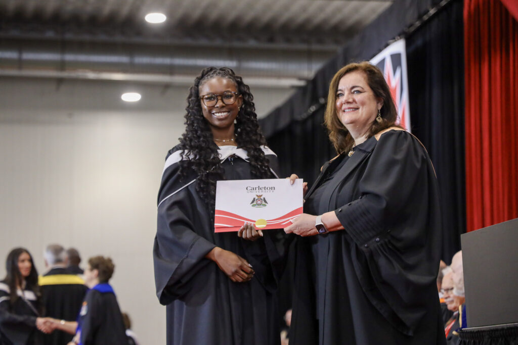 A graduate poses for a photo with Suzanne Blanchard on stage at Convocation.