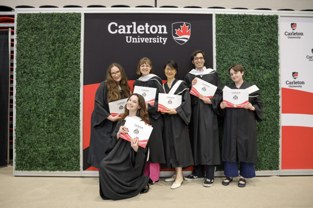 A group of graduates posing with their diplomas at Convocation.