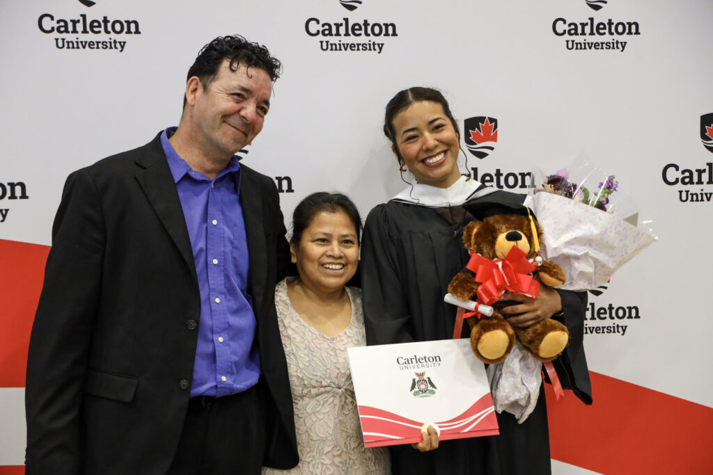 A graduate posing with loved ones at Convocation.