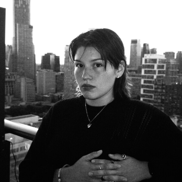 Black and white photo of short haired student standing in front of city skyline