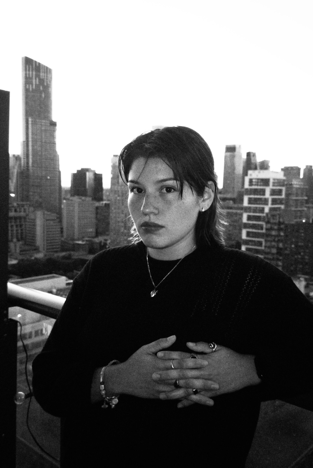 Black and white photo of short haired student standing in front of city skyline