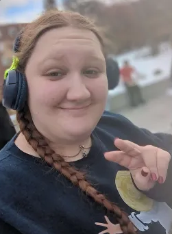 Student posing with peace sign, braids and headphones