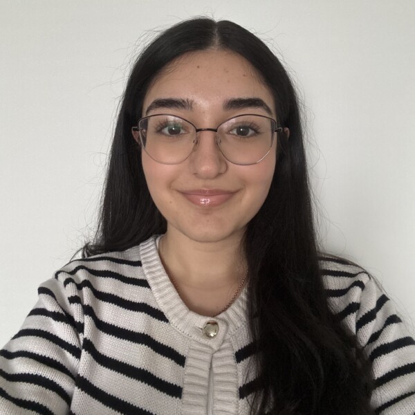 Student with long dark hair, striped sweater and glasses