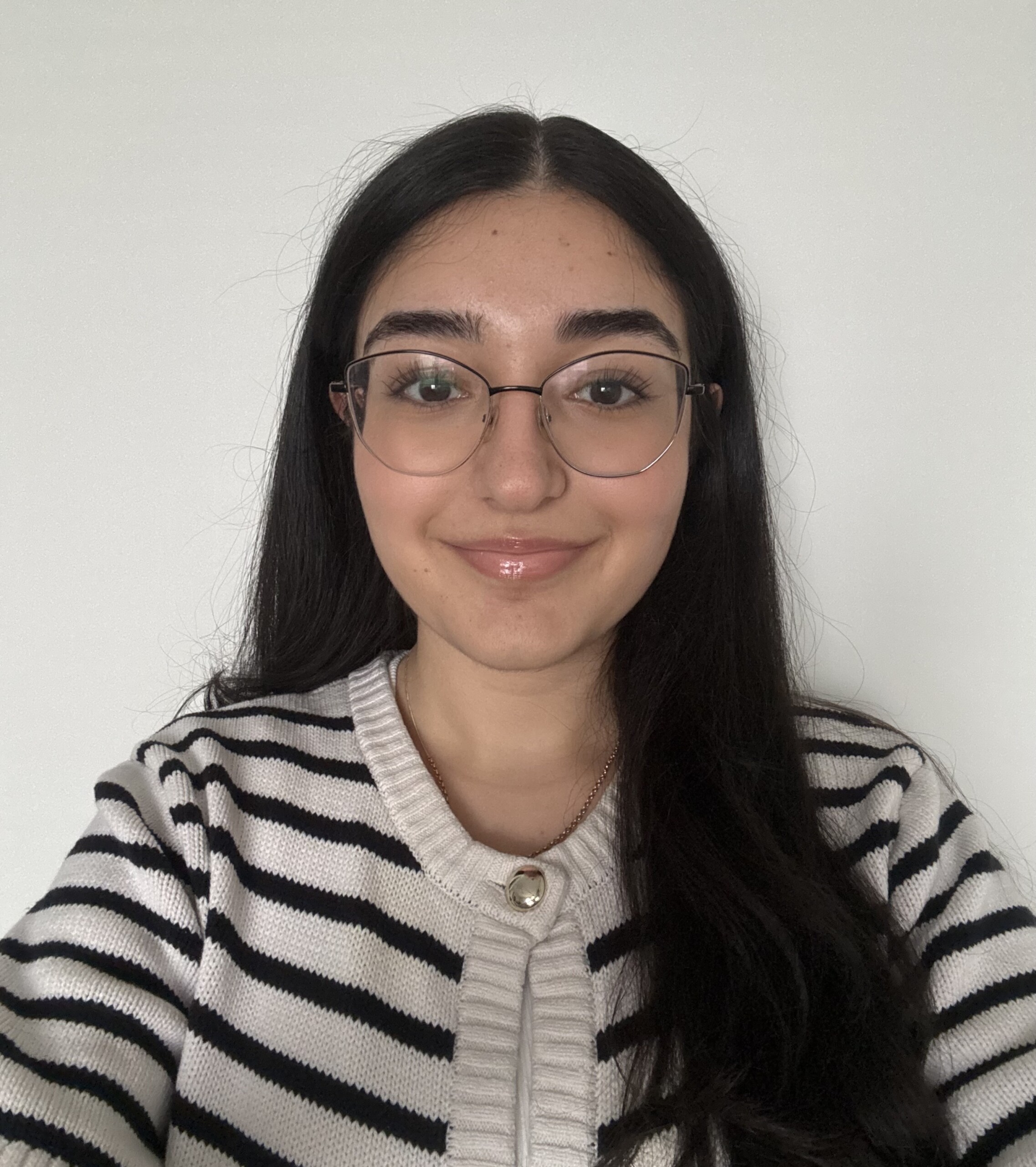 Student with long dark hair, striped sweater and glasses