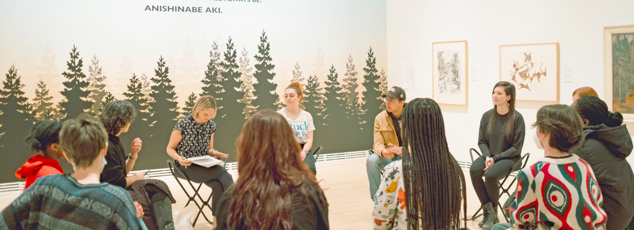 A group of people sitting in a circle in an art gallery.