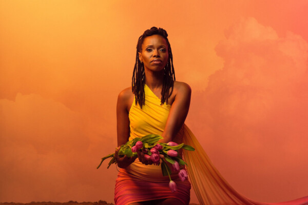 Musician Kellylee Evans kneeling holding flowers.