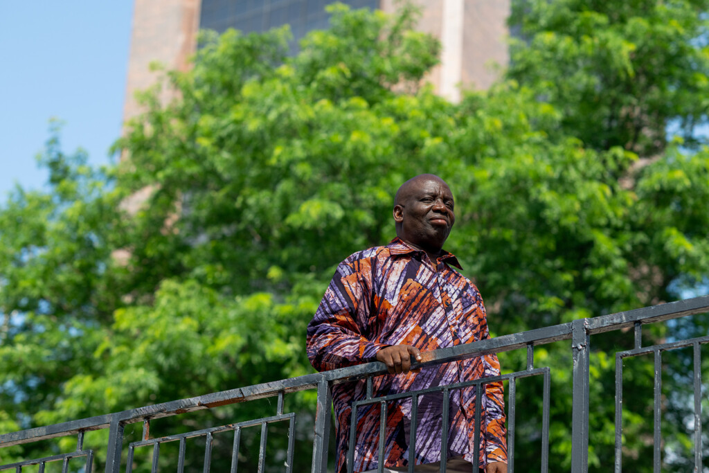 Samuel Ojo Oloruntoba leaning on a railing in the Carleton quad.