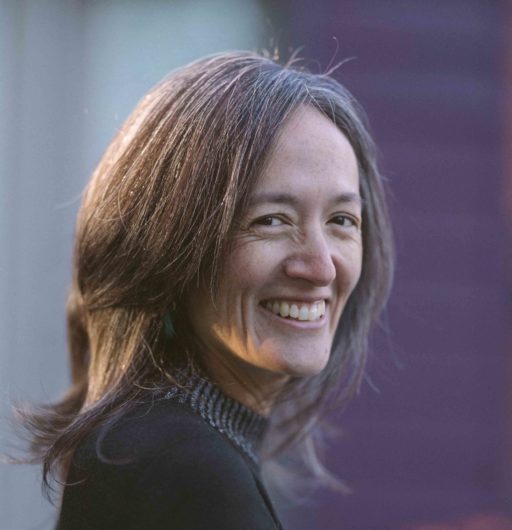 A colour portrait shows a person with shoulder-length hair looking toward the camera against a softly blurred background.