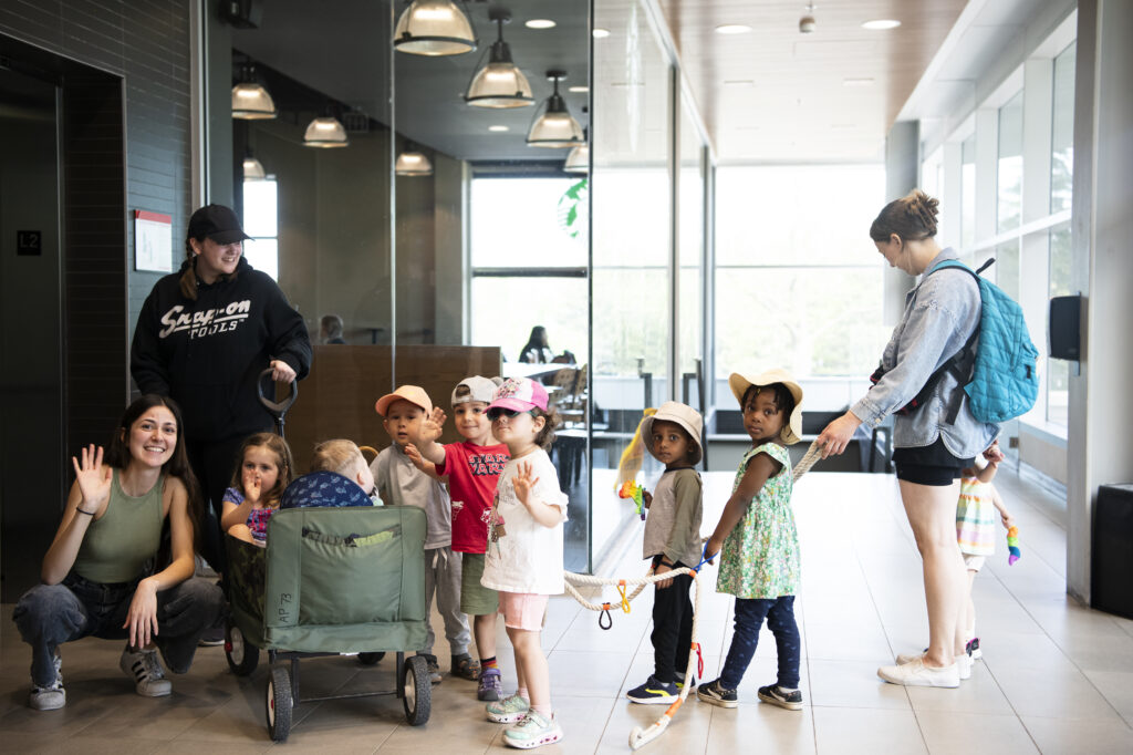 Dilara Erver (left, front) and Flora Morais (far right) with some of the enthusiastic Colonel By Child Care Centre readers and an educational assistant, waiting for the elevator outside the Carleton University Library.