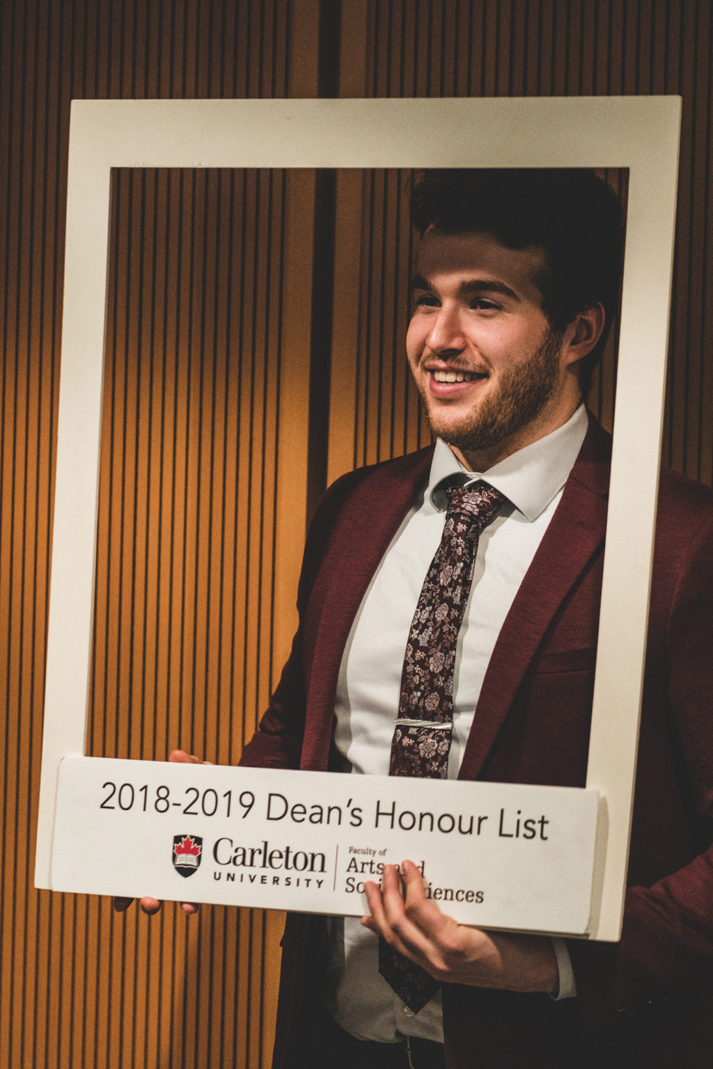 male student poses with Honour List sign 