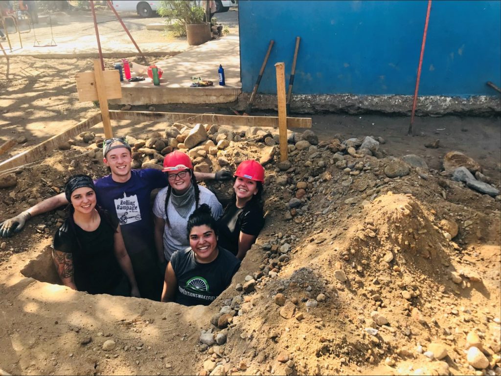 students wearing helmets in a big foundation hole