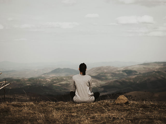 person sitting on a rock by a lake alone