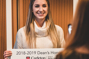 a female student holding a dean's list sign
