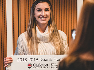 a female student holding a dean's list sign