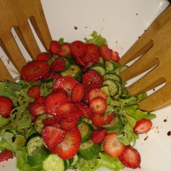 A balsamic strawberry garden salad with large wooden salad forks.