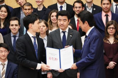 A student presents a certificate to Prime Minister Abe Shenzo as Ali Bahman looks on.