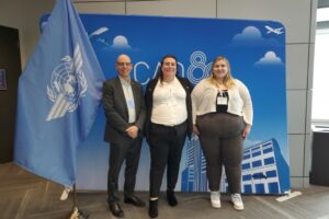 Marc Rioux, Rory Palau Zea and Jaimi Platter stand in front of a UN flag.