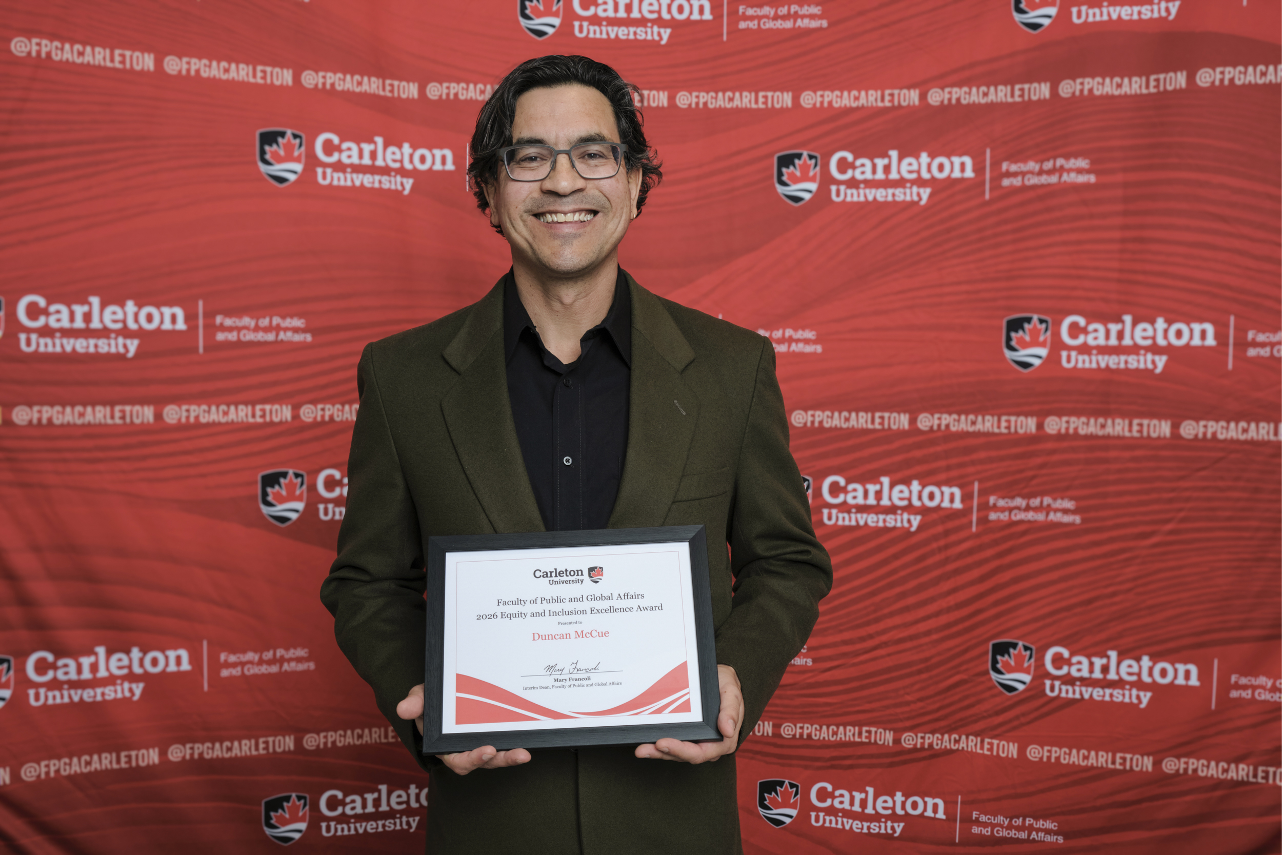 Duncan McCue poses with the 2026 Equity and Inclusion Excellence Award