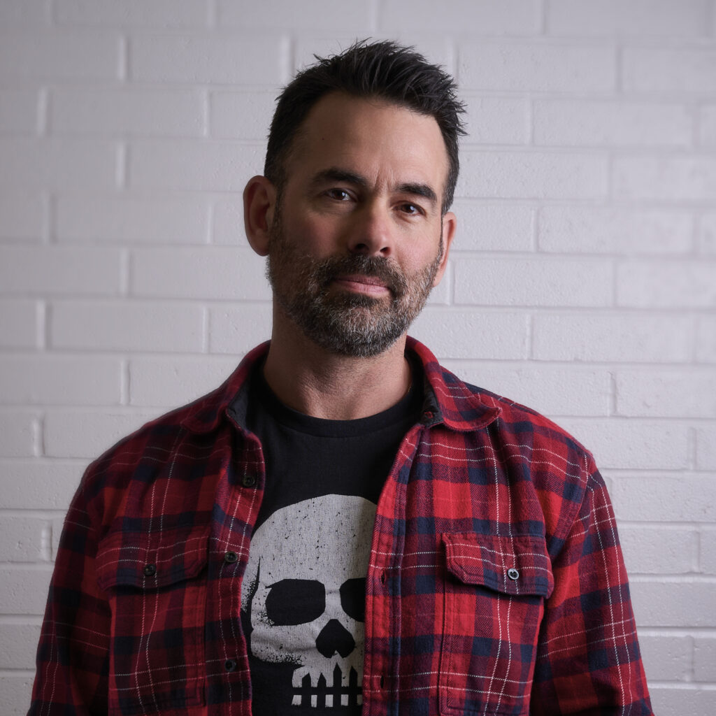 Photo of author Josh Greenberg against a white brick wall