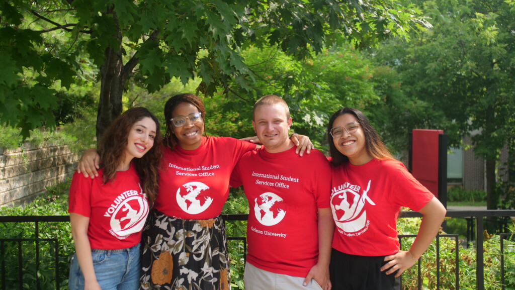 Four students wearing their red volunteer shirts posing for a group shot.