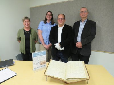 photo of four people standing in front of a book