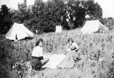 black and white photo of two girl guides pitching a tent in a field