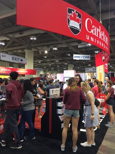 students standing in front of Carleton booth asking questions