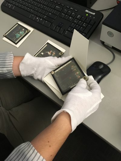 person wearing white gloves handling a photograph