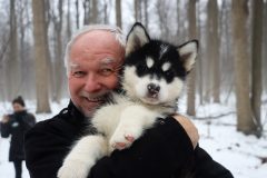 Rod Phillips outside in the winter holding a husky puppy