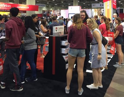 students standing in front of Carleton booth asking questions