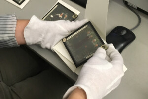 hands in white gloves holding a photograph