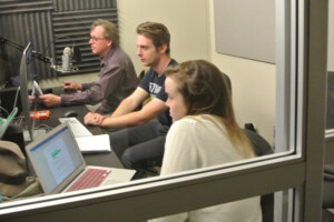 three people facing a microcu_people_phone and a computer screen