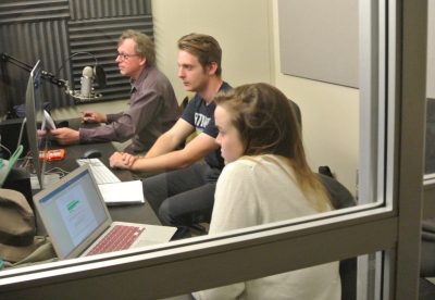three people facing a microcu_people_phone and a computer screen