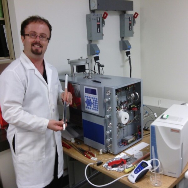 Danien Huffer wearing a labcoat standing next to a computer