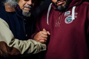 Jalal Nuriddin and Malik Al Nasir clasping hands while facing the camera