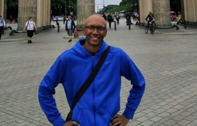 student in blue sweatshirt standing outdoors