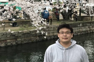 Ken Yoshida in front of cherry blossom trees