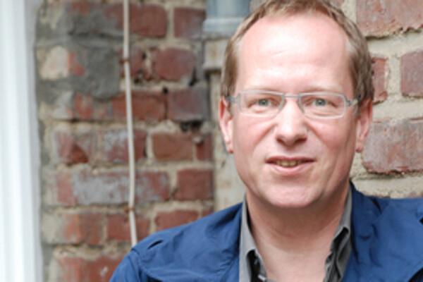 Til van Rahden standing in front of a brick wall