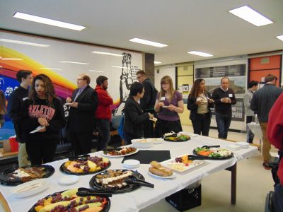 students and faculty networking around a reception table