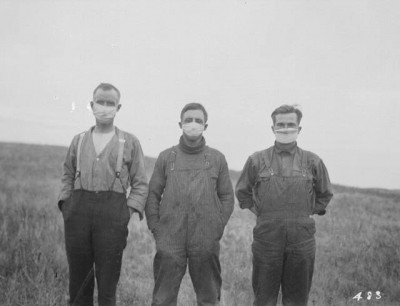 Men in field wearing surgical masks