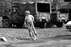 child cycling in front of armoured vehicles