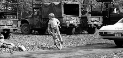 child cycling in front of armoured vehicles