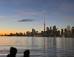 Two people by the water with the city line in the background