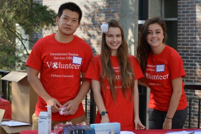 3 volunteers wearing red shirts at a table